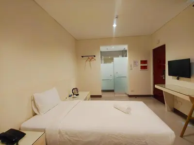 a bedroom with a bed and a desk and a television at Kaizen Suites in Manila