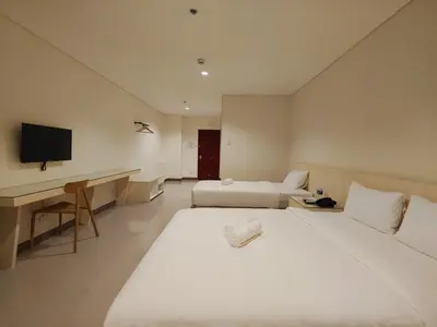 a hotel room with two beds and a desk and a television at Kaizen Suites in Manila