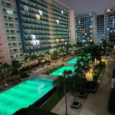 an overhead view of a pool with palm trees and buildings at Bliss Staycation at Sea Residences by John in Manila