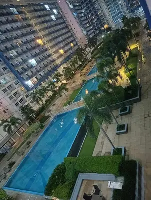 an overhead view of a large pool with palm trees and buildings at Bliss Staycation at Sea Residences by John in Manila
