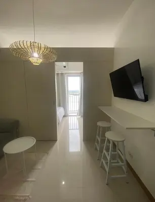 a living room with a table and stools and a television at 1BR unit in South Residence Las Pinas with Wifi & Netflix in Manila