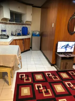 a kitchen with a table and a tv on a counter at THE MANSION - 24-HOUR Near AirPort Hostel 4 Backpackers in Manila