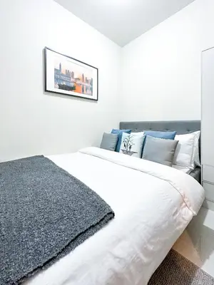 a white bedroom with a large white bed with blue pillows at 1 Bedroom Condo near CCP Roxas Boulevard Pasay in Manila