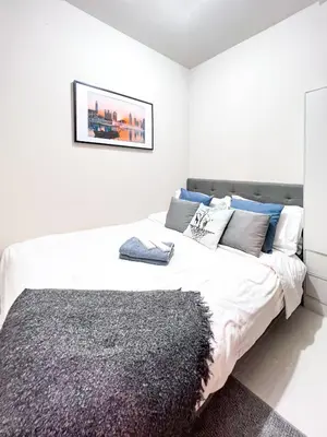 a white bedroom with a large bed with blue pillows at 1 Bedroom Condo near CCP Roxas Boulevard Pasay in Manila