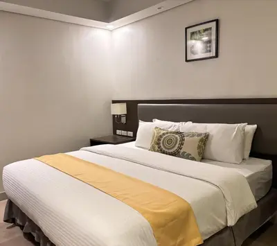 a bedroom with a large bed with white and yellow sheets at The Residences at BCCT in Manila