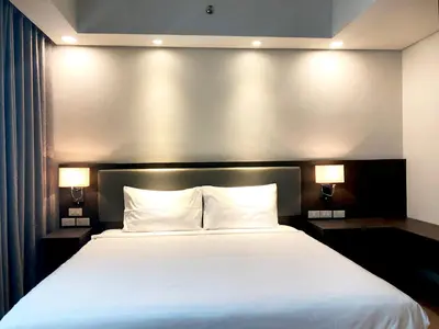 a bedroom with a large white bed with two lamps at The Residences at BCCT in Manila