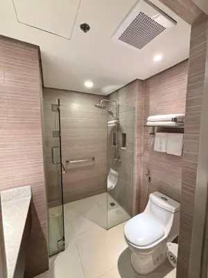 a bathroom with a toilet and a glass shower at The Residences at BCCT in Manila