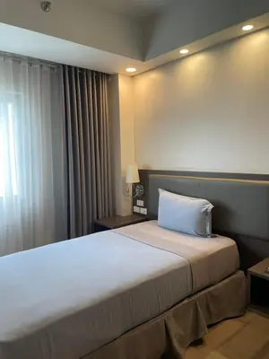 a hotel room with a large bed with a window at The Residences at BCCT in Manila
