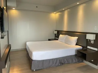 a bedroom with a large white bed and a television at The Residences at BCCT in Manila