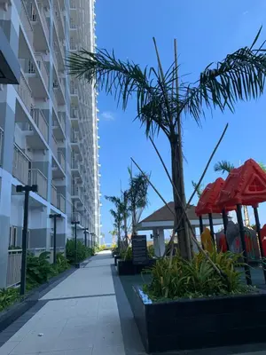 a walkway in front of a building with a palm tree at SMDC Coast Residences Roxas Boulevard corner Pasay Condo Unit in Manila