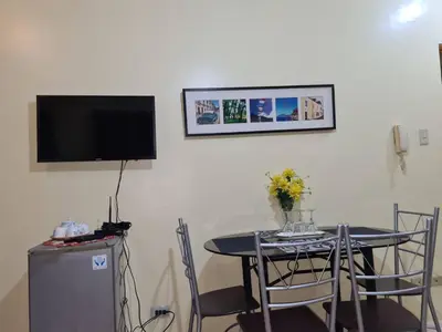 a dining room with a table and a tv on the wall at Pet Friendly Staycation in in Cainta