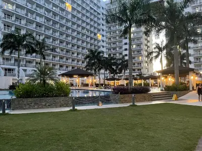 a large building with a swimming pool in a park at Amour Staycation Shell residences in Manila