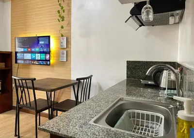 a kitchen with a sink and a table with chairs at Althea's Cozy Home - Condo in Las Pinas in Manila