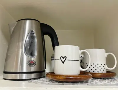 two coffee cups sitting on a counter next to a toaster at Althea's Cozy Home - Condo in Las Pinas in Manila