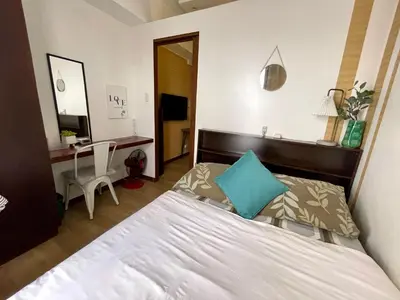 a bedroom with a bed and a desk and a mirror at Althea's Cozy Home - Condo in Las Pinas in Manila