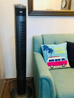 a black floor lamp next to a couch with a pillow at Air residence 1BR with balcony FREE NETFLIX in Manila