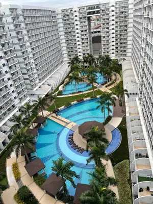 an aerial view of a resort pool with palm trees and buildings at Amour Staycation Shell residences in Manila