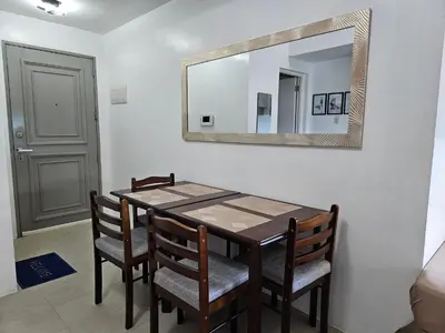 a dining room table with chairs and a mirror at Spacious Studios in Manila