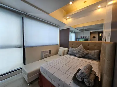 a bedroom with a bed and a large window at Spacious Studios in Manila