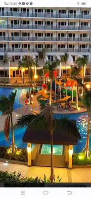 a large building with palm trees and a swimming pool at vin's place 1br amenities view at Shell Residence in Manila