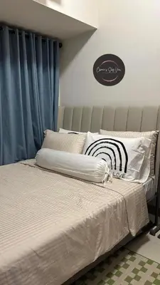 a bedroom with a large bed with blue curtains at SMDC Coast Residences near PICC in Manila