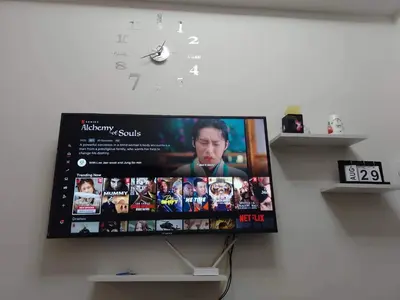 a flat screen tv hanging on a wall with a clock at Pasay Coast Residences JCMJ in Manila