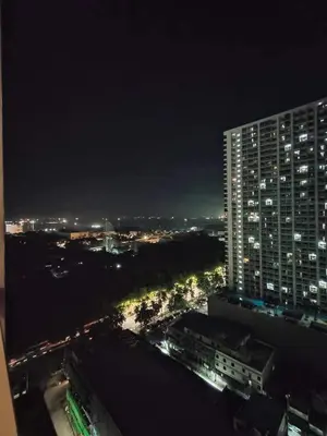 a view of a city at night with a tall building at Pasay Coast Residences JCMJ in Manila