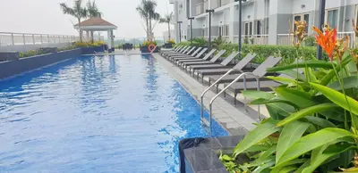 a hotel swimming pool with lounge chairs and a gazebo at Pasay Coast Residences JCMJ in Manila