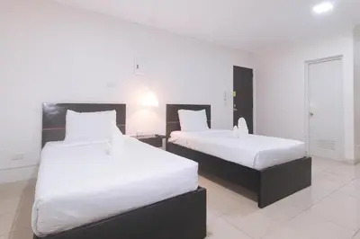 two beds in a hotel room with white sheets at Propiedad Residences Makati in Manila