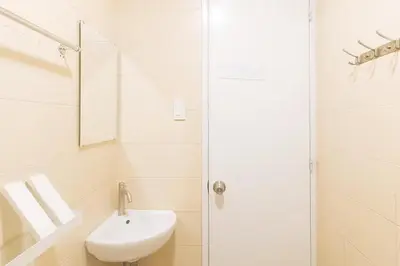 a white bathroom with a sink and a shower at Propiedad Residences Makati in Manila