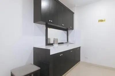 a kitchen with black cabinets and a sink and a stool at Propiedad Residences Makati in Manila