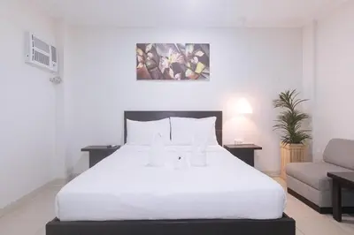 a bedroom with a white bed and a couch at Propiedad Residences Makati in Manila
