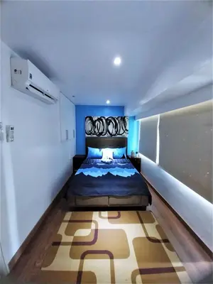 a bedroom with a large bed in a blue room at 2 BR loft-type condo Fort Victoria in Manila