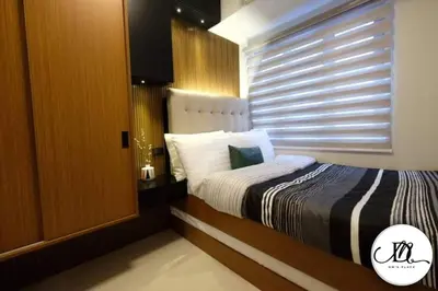 a bedroom with a bed and a window with blinds at DM's Place at S Residences MOA in Manila
