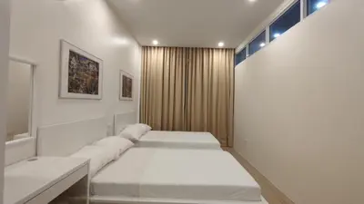 a white bedroom with two beds and a window at Addie's Place Camella Homes 2D Muntinlupa in Manila