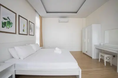 a white bedroom with a white bed and a desk at Addie's Place Camella Homes 2D Muntinlupa in Manila