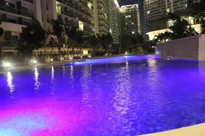 a pool with purple lights in a city at night at Azure Urban Resort Residence A1 in Manila