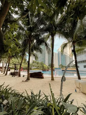 a beach with palm trees and the ocean and buildings at Downtown Nook - Azure Urban Resort Residences in Manila