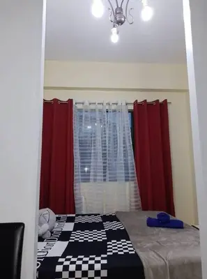 a room with a bed with red curtains and a window at Affordable Transient along Ortigas Ext in Cainta