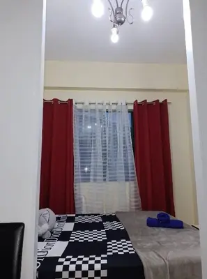 a bedroom with a bed with red curtains and a window at Budget Friendly Condo for Rent in Valley Mansions in Cainta