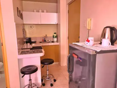 a small kitchen with two stools and a refrigerator at Budget Friendly Condo for Rent in Valley Mansions in Cainta