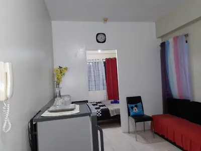 a living room with a red couch and a bed at Pet Friendly Staycation near Villa Ardin in Cainta