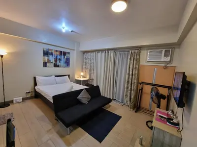 a bedroom with a bed and a couch in a room at Palm Tree Villas Condominium by Beth in Manila