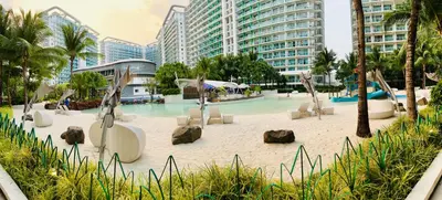 a pool with chairs and rocks in a resort at Azure Pool View with Balcony, WiFi and Netflix in Manila