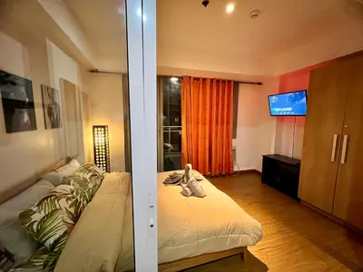 a room with a bed and a tv in it at Azure Pool View with Balcony, WiFi and Netflix in Manila