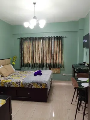 a bedroom with a bed and a table and a window at Pet Friendly Transient in Valley Golf near Emperor Events Place in Cainta