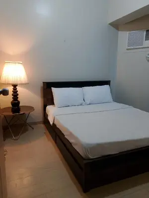 a bedroom with a bed and a lamp on a table at Roxas Blvd Stunning Studio Condo Near US Embassy in Manila