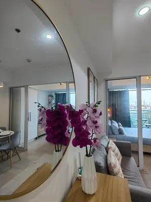a living room with a mirror and purple flowers on a table at Happirest at Azure Urban Resort Residences, Paranaque City in Manila