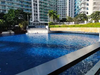 a pool of blue water in a city with tall buildings at Happirest at Azure Urban Resort Residences, Paranaque City in Manila