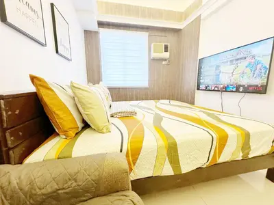 a bedroom with a bed with a tv on the wall at King Bed Suite at Pine Crest #T3-439 near Mall in Manila